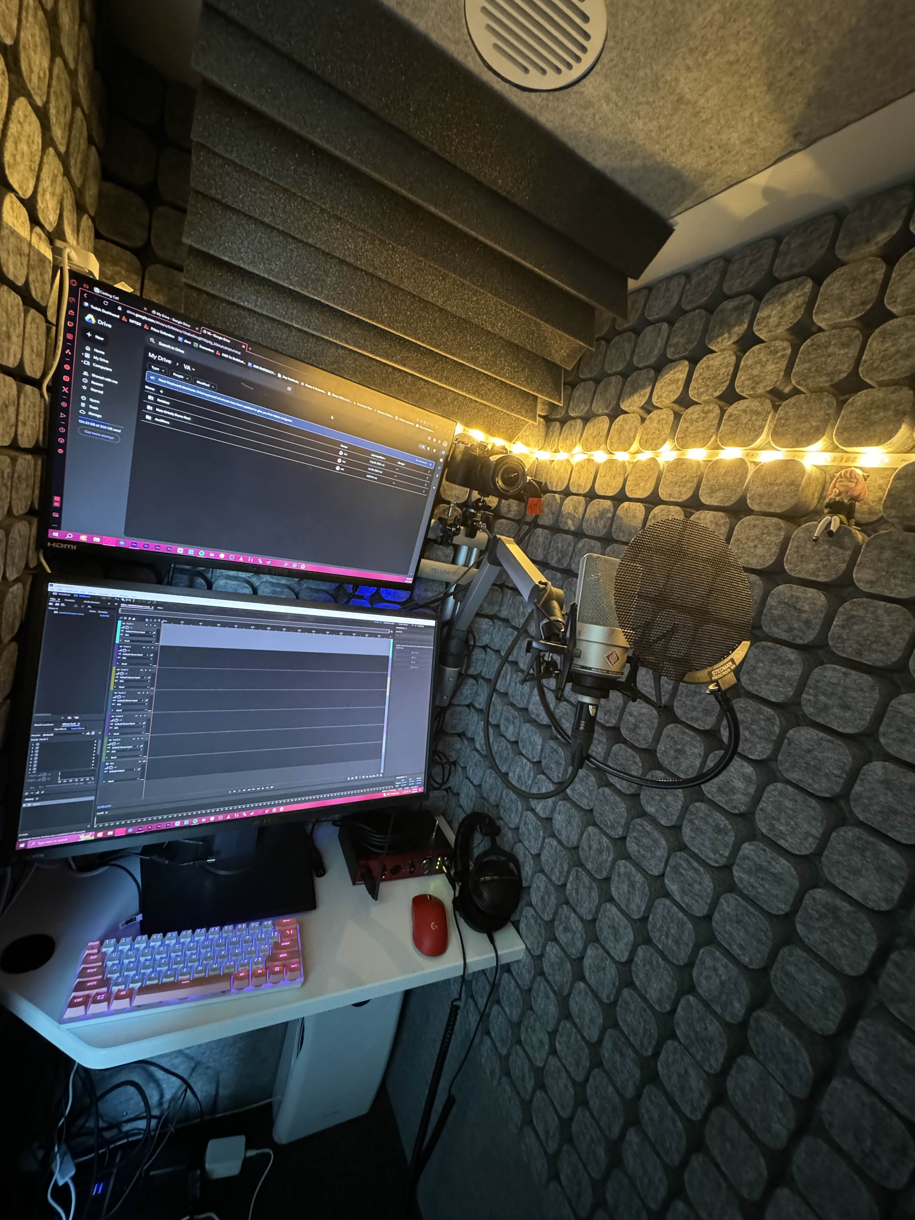 A computer and microphone in a padded audio recording booth